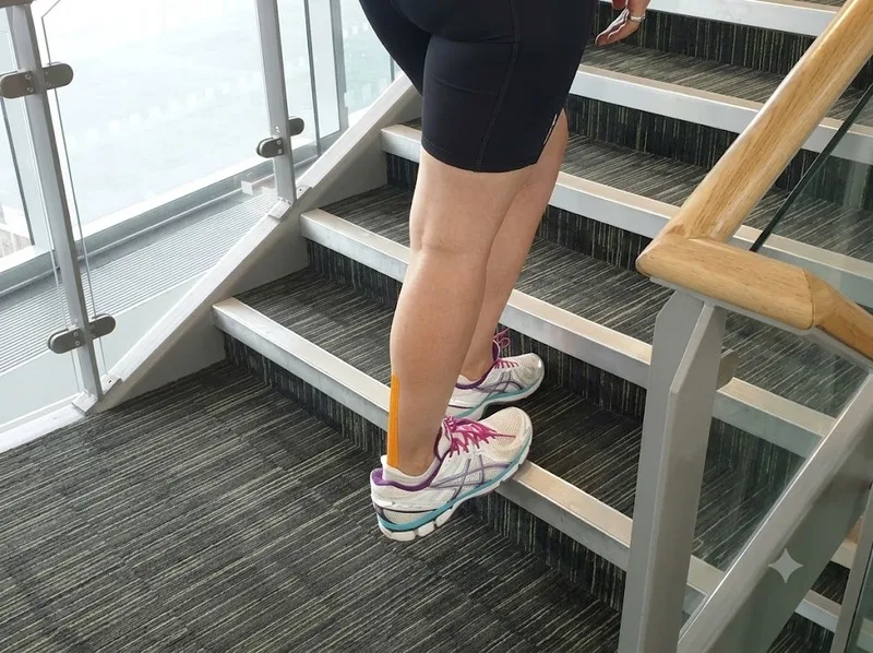 Giãn cơ bắp chân trên bậc thấp cần giữ thăng bằng và kiểm soát gót.